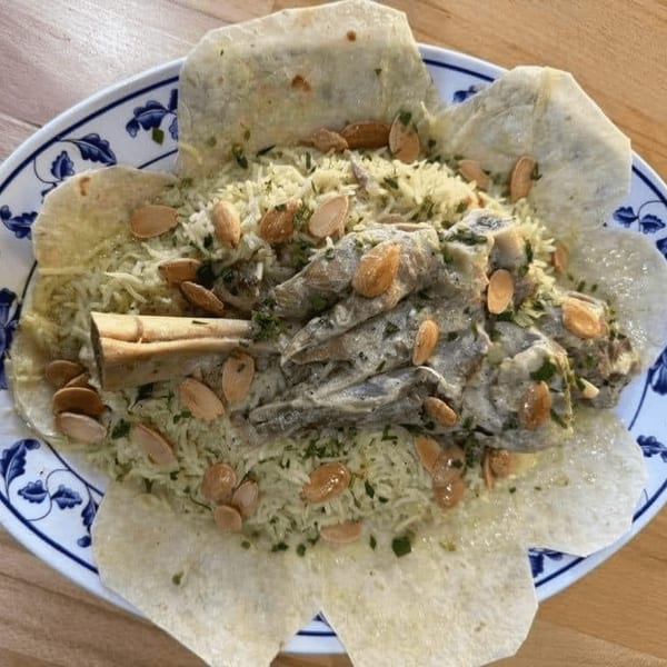 Ali Baba Kabab's Mediterranean dish with lamb shank, rice, and almonds on a decorative plate.