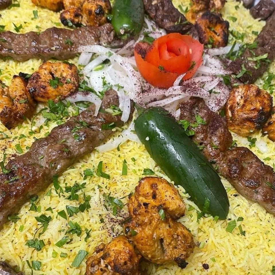 Ali Baba Kabab's platter with grilled chicken and beef kababs, rice, onions, and a tomato rose.