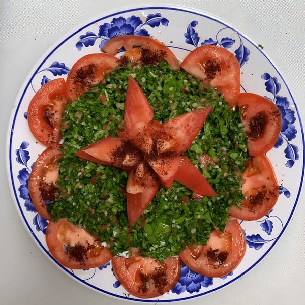 A vibrant Ali Baba Kabab tabbouleh salad with fresh parsley, tomatoes, and spices on a decorative plate.